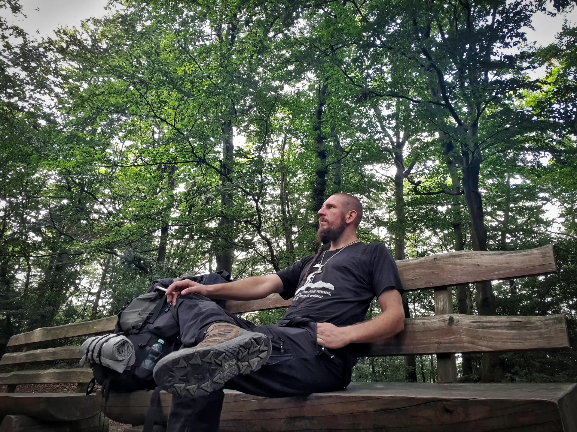 Gründer David sitzend auf der Bank mit Wanderrucksack.